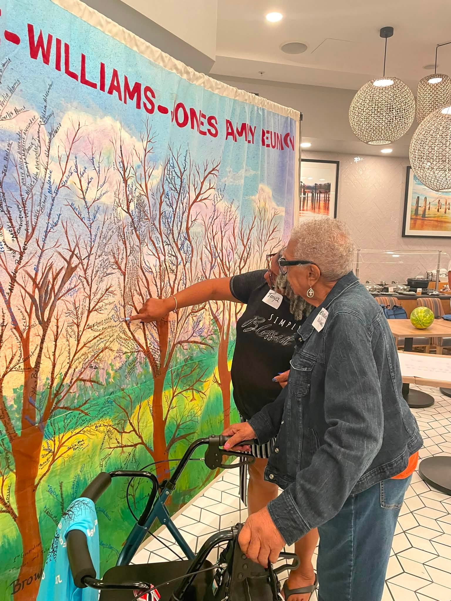 Family members pointing to names and branches on a family reunion tapestry