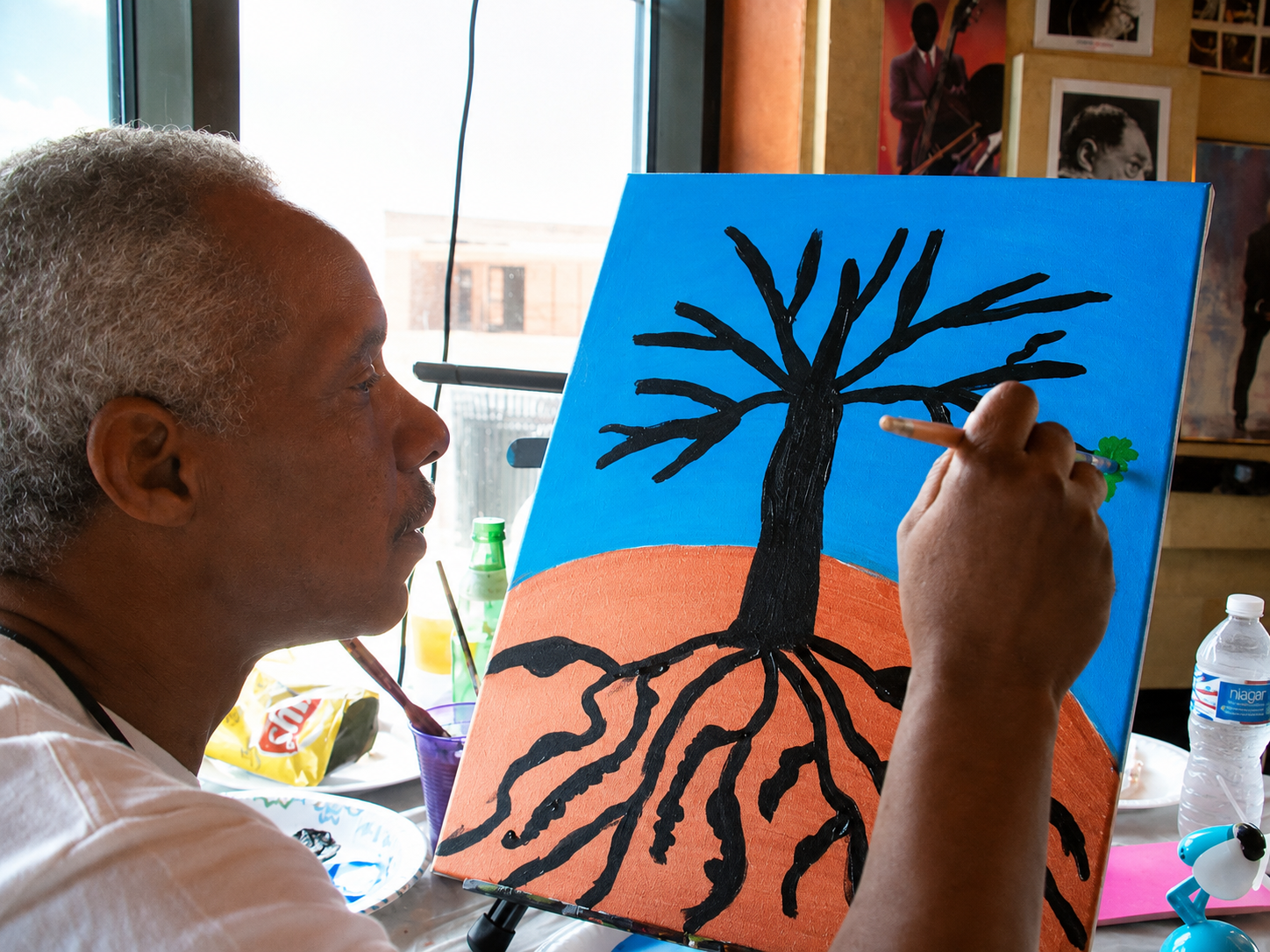 An adult family member painting a tree with deep roots during a family gathering